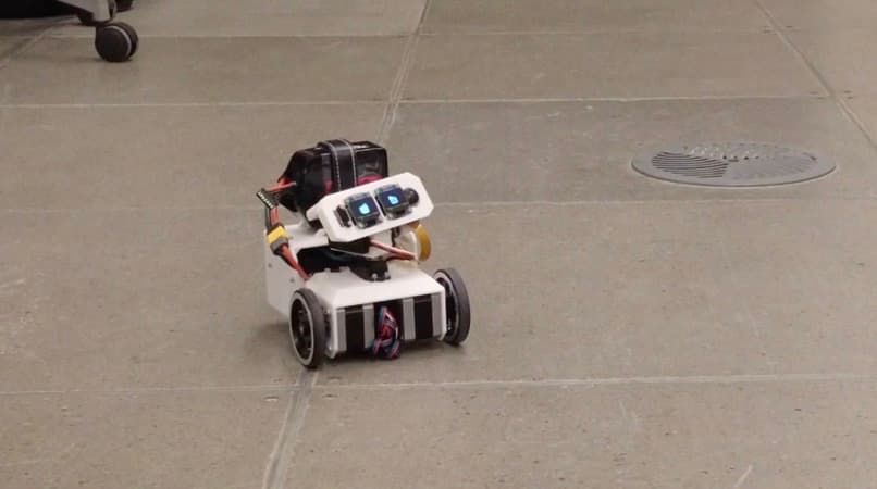Blinky Face, a small two-wheeled robot with two blue LCD eyes, balanced on a concrete floor.